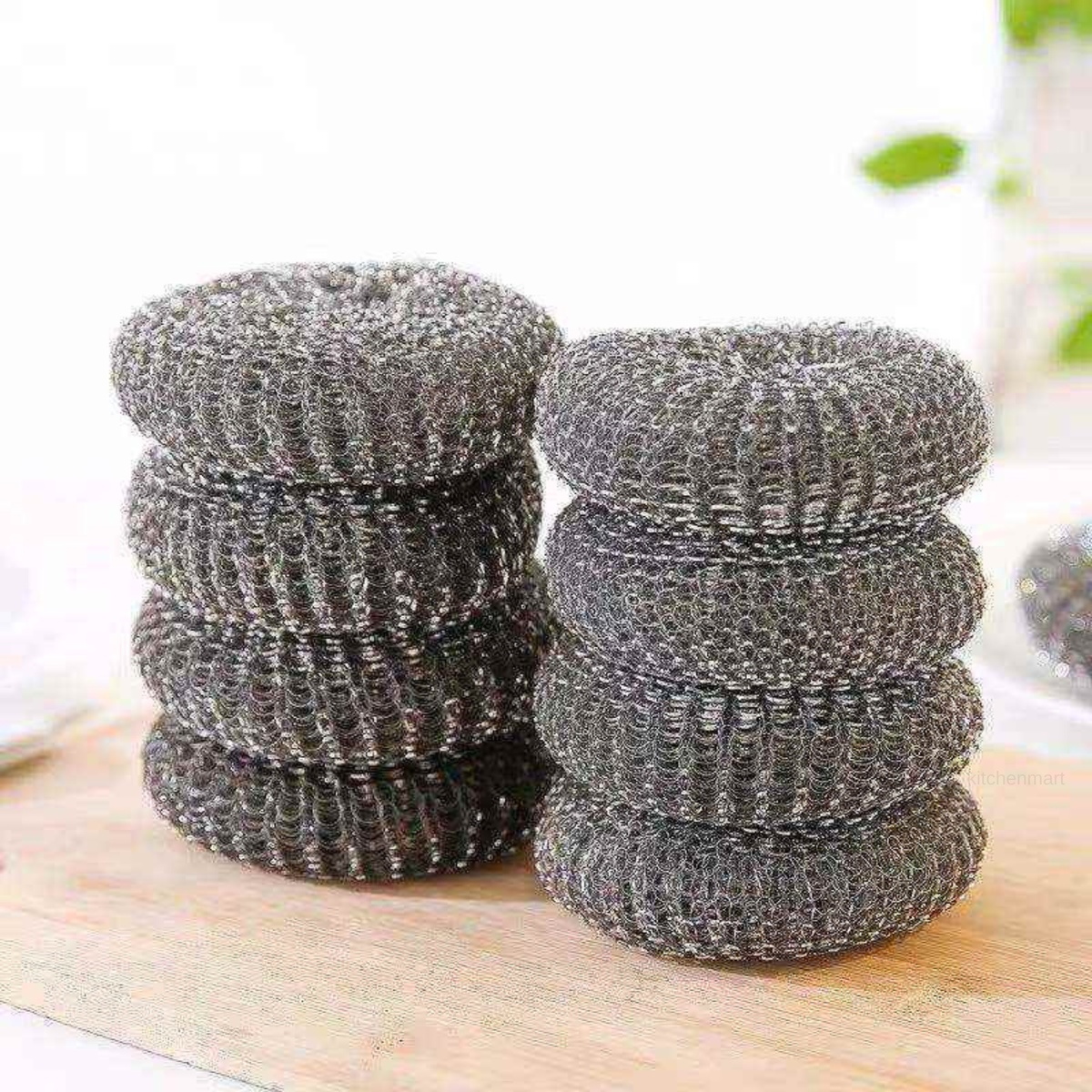Stacks of metal scrubber pads on a wooden surface with a blurred background