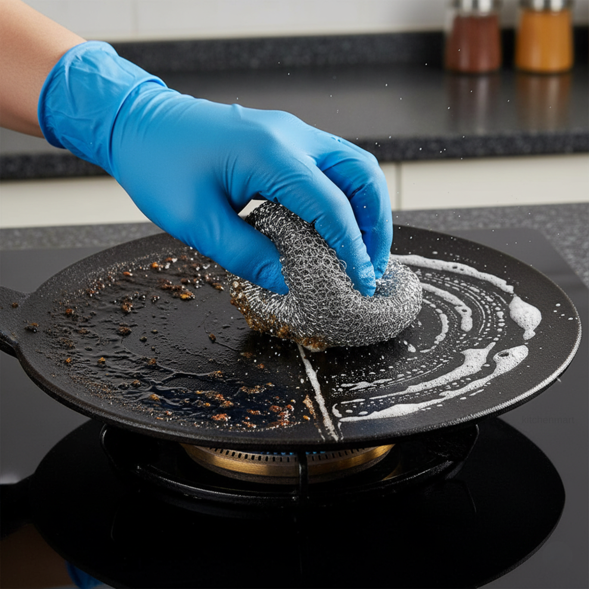 Person cleaning a black stovetop with a scrubber and blue gloves.
