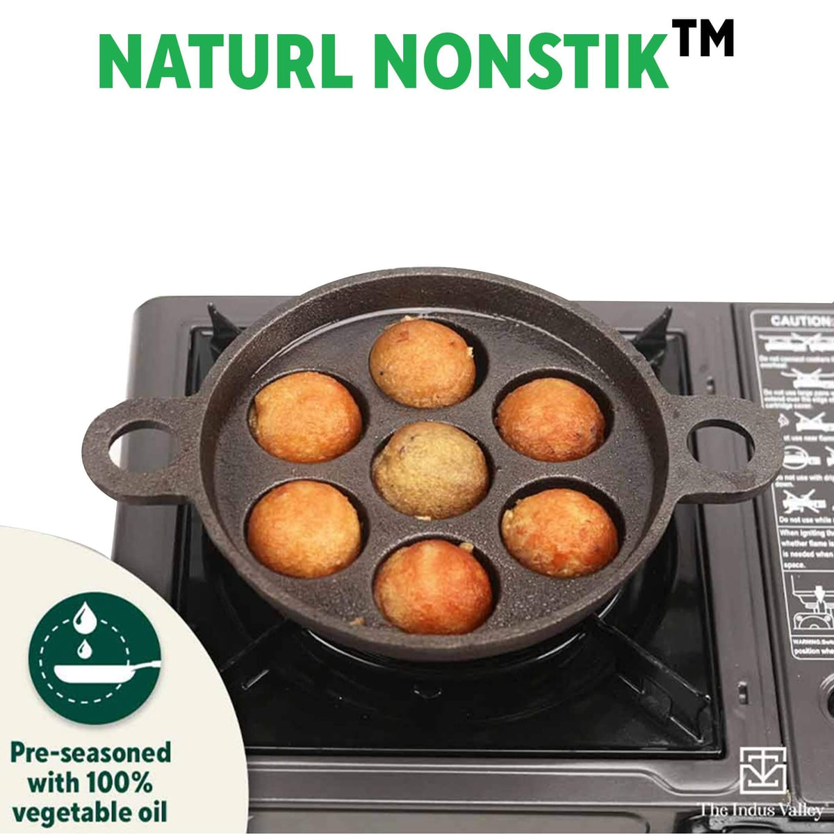 Indus Valley Cast Iron Paniyaram Pan with 7 pits on a stove, pre-seasoned for easy cooking and non-stick performance.