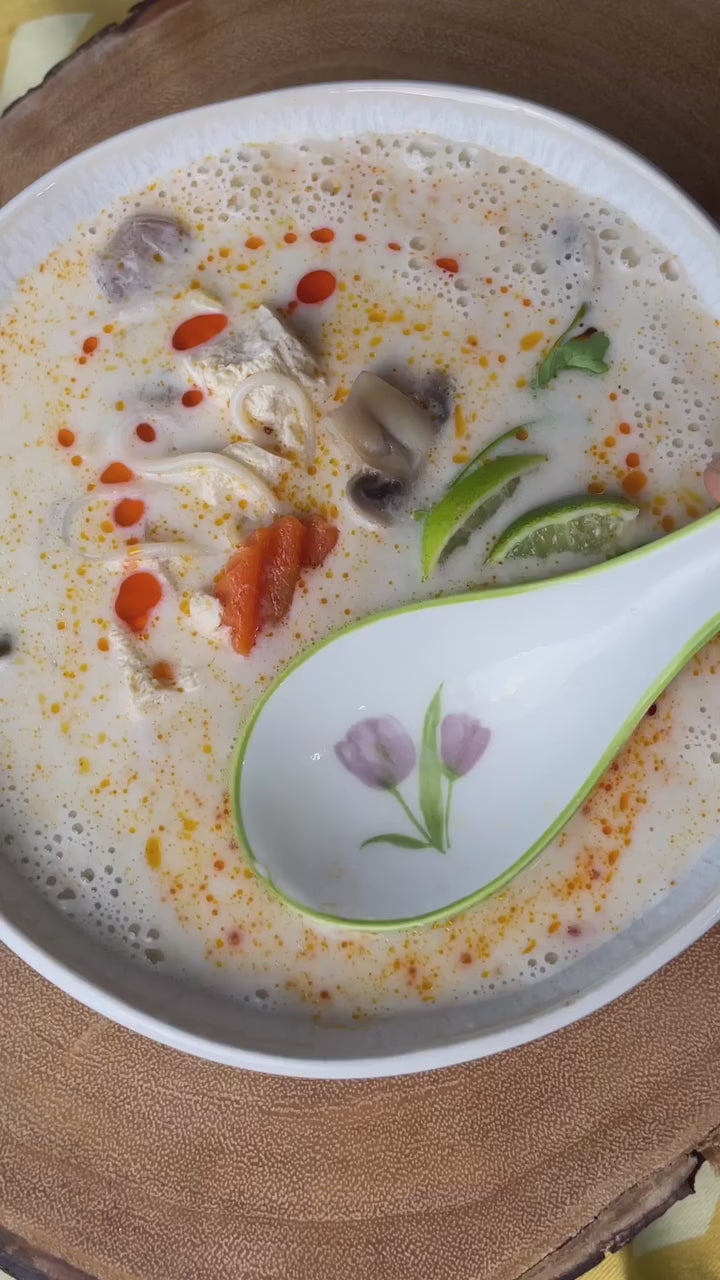 Delicious bowl of creamy soup with vegetables, herbs, and spices, served with a decorative spoon.